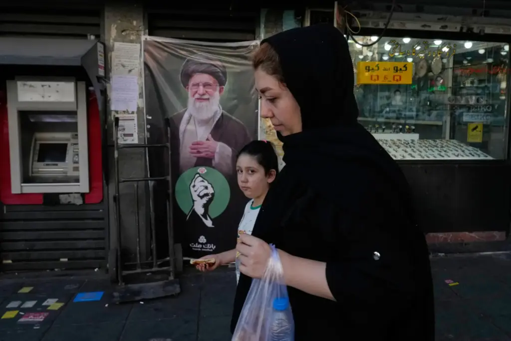 People pass a portrait of the late Iranian Supreme Leader...