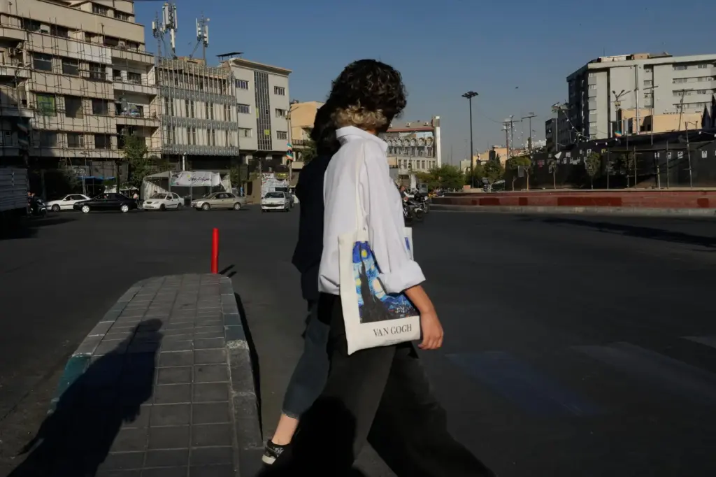 Women walk at the Islamic Revolution square in downtown Tehran,...