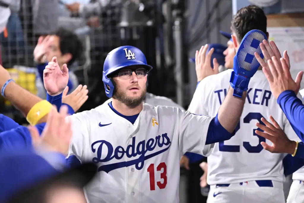 Dodgers third baseman Max Muncy high-fives teammates after scoring on...