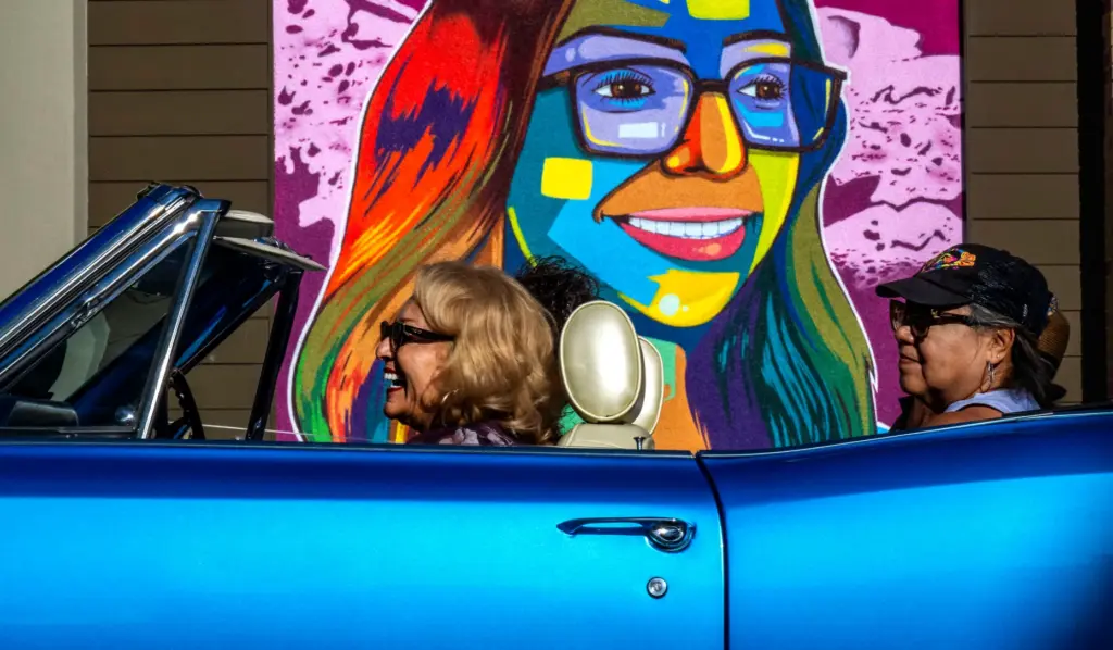 Classic car enthusiasts cruise in a blue Chevy while enjoying...