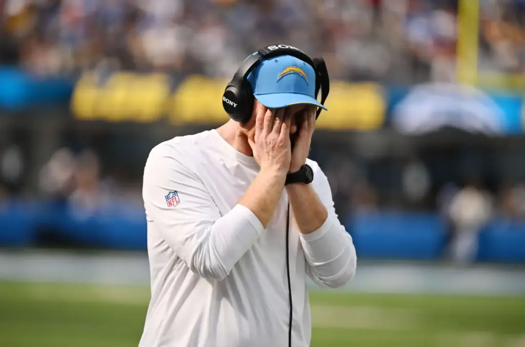 Chargers offensive line coach Butch Barry holds his face after...