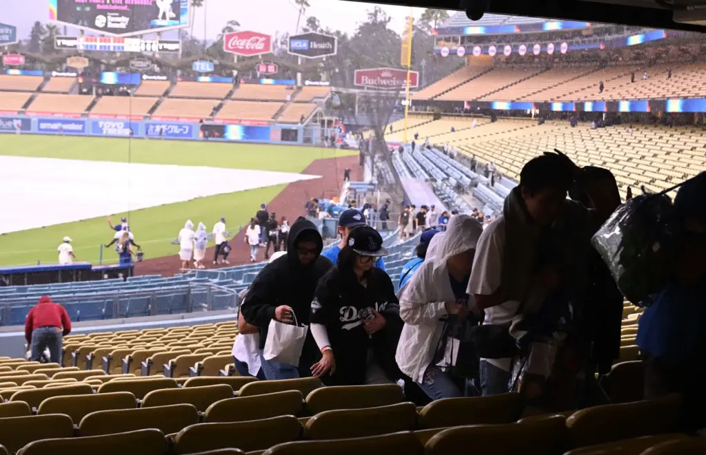 People rush from the stands as rain falls before the...