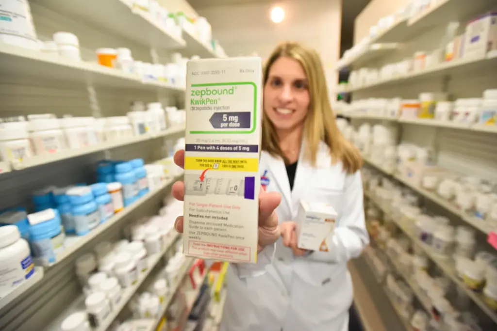 Pharmacist Sarah Ferry holds up A package of GLP-1 medication...