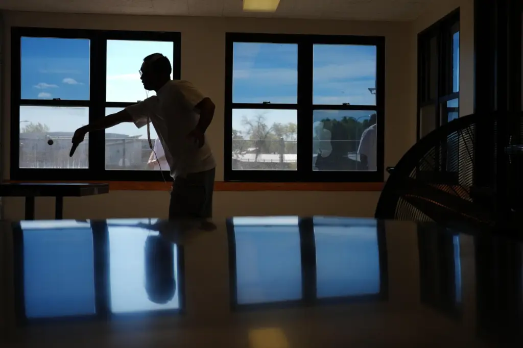 A person who is incarcerated plays ping pong while some...