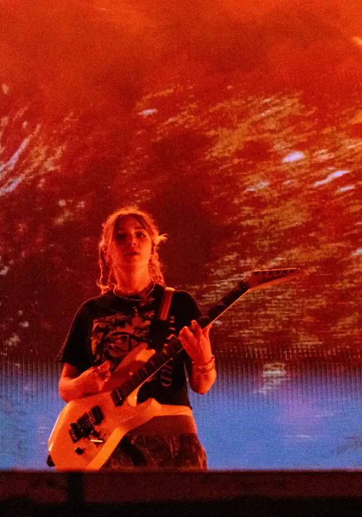 Meg Mills plays the guitar as Turnstileâs visuals change behind...