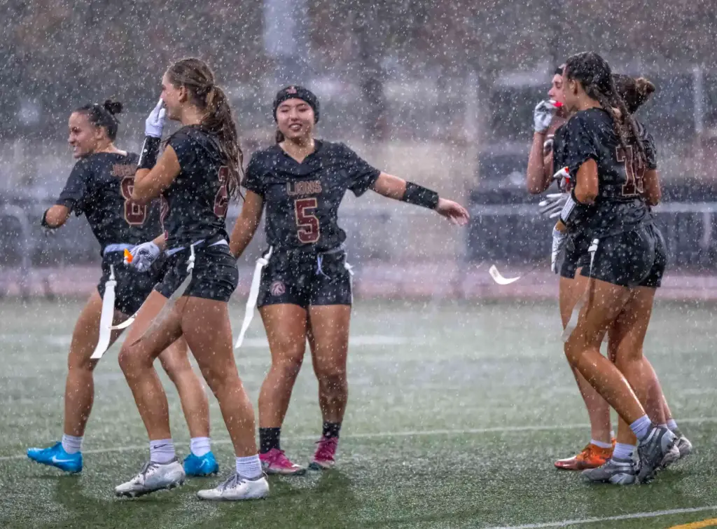 JSerra players celebrate a touchdown during a downpour of rain...