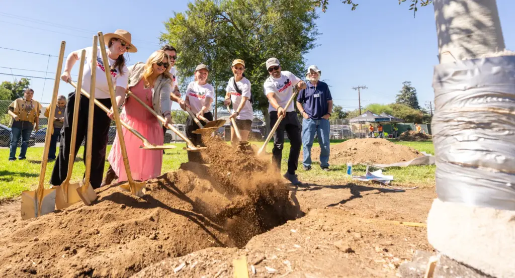 Disney Volunteers dig dirt during a ceremonial tree planting during...