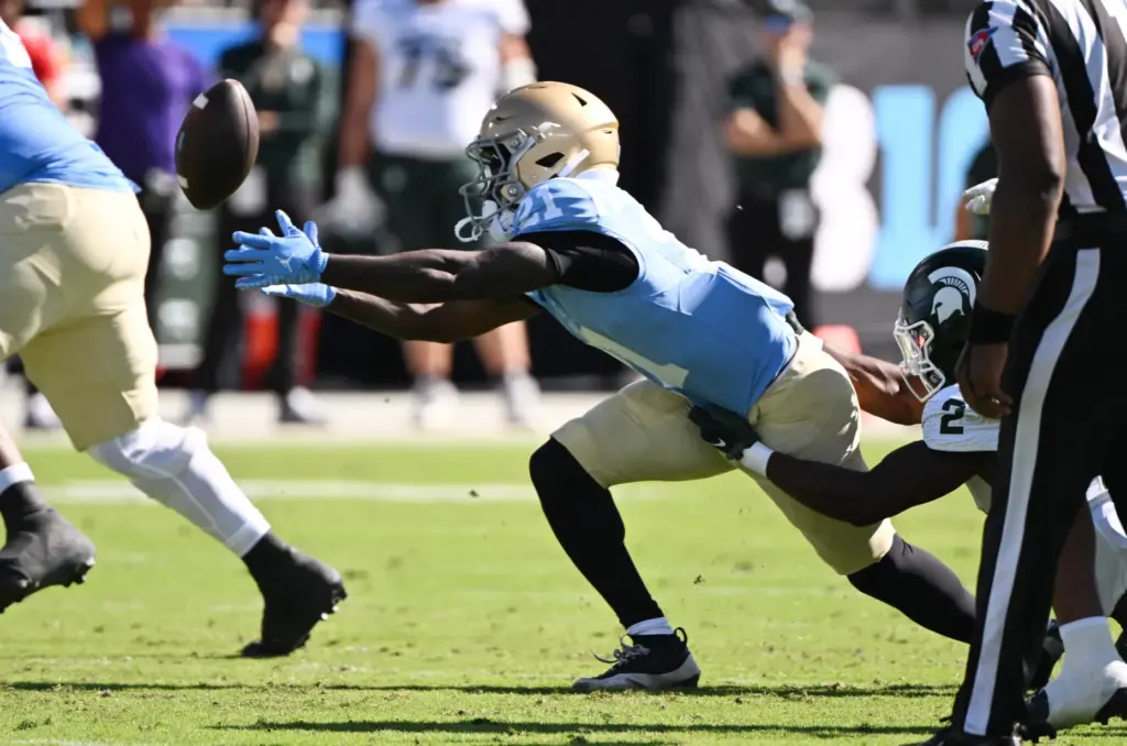 UCLA running back Jaivian Thomas (21) fumbles the ball, which...