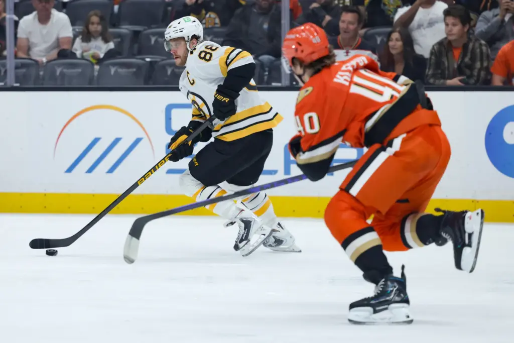 Boston Bruins right wing David Pastrnak, left, moves the puck...