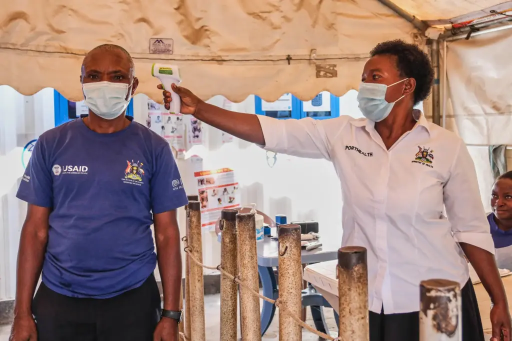 A health worker checks an individual's temperature at a temporary health clinic.