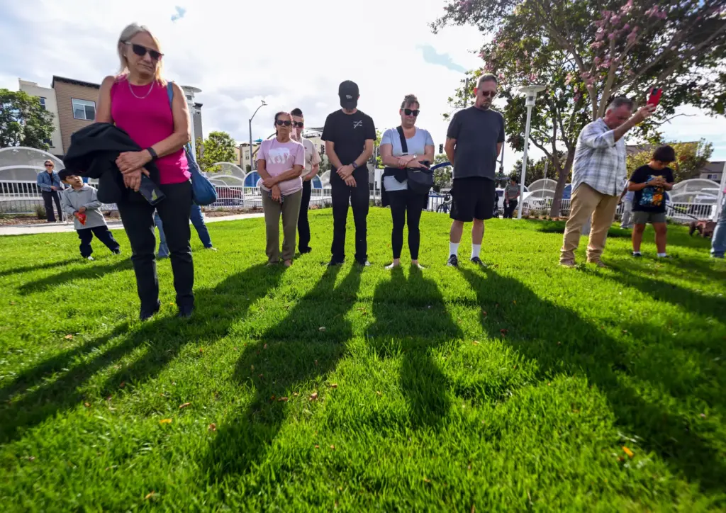 People bow their heads as Costa Mesa Police Chaplin Dave...