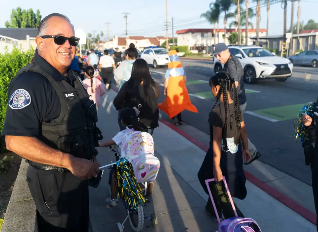 Westminster Police officer Manny Nunez greets walkers at Schmitt Elementary...