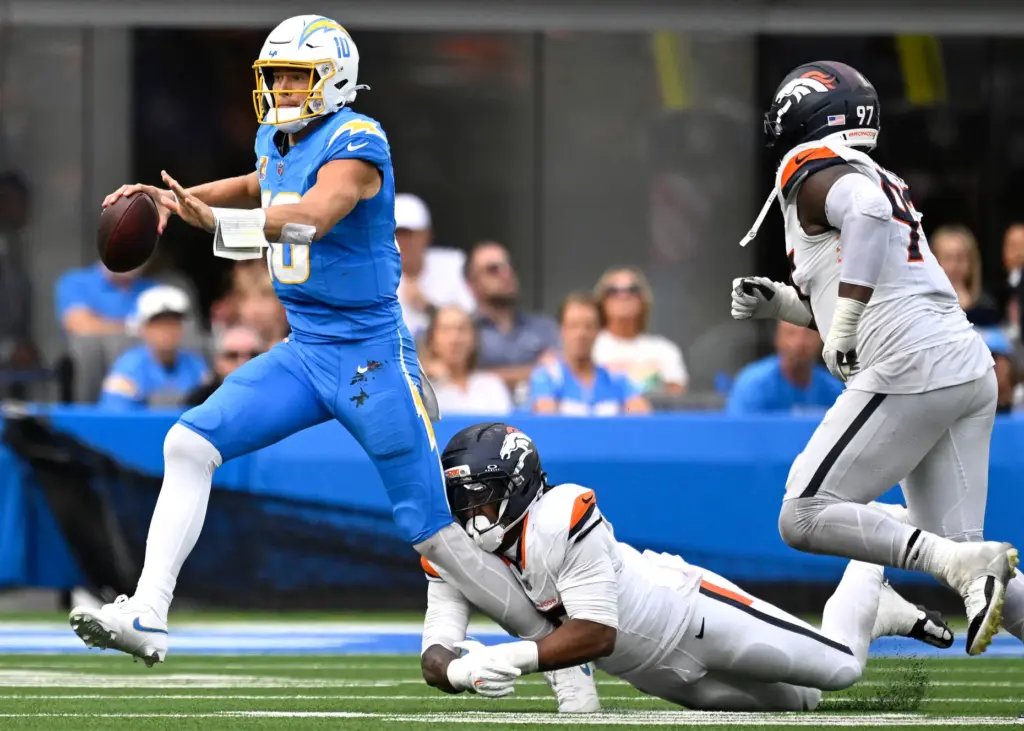 Chargers quarterback Justin Herbert (10) can not escape the grasp...