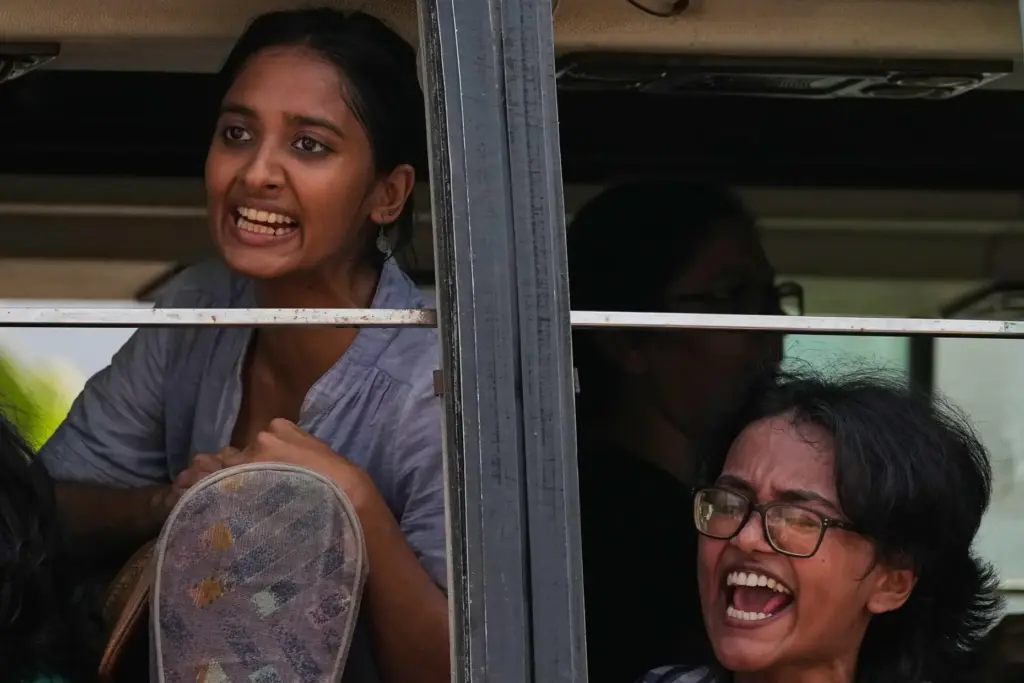 Detained youth protesters shout slogans as police drive them away in a van.