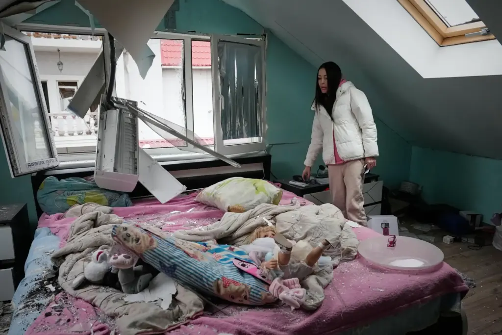 A woman looks at her damaged apartment after a Russian...