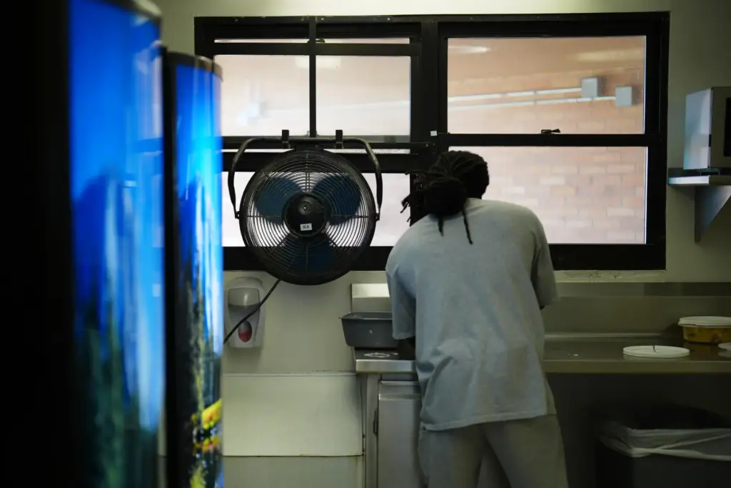 A fan blows air inside while a person who is...