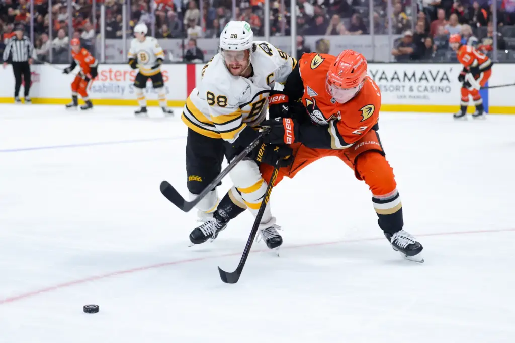 Ducks defenseman Jackson LaCombe, right, and Boston Bruins right wing...