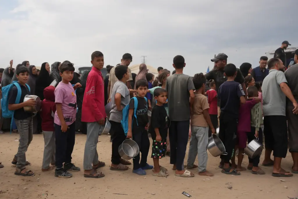 Palestinians line up to receive food donated by the World...