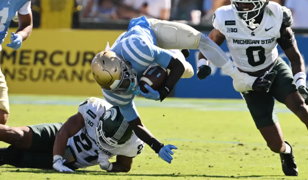 UCLA running back Anthony Woods (6) is upended by Michigan...
