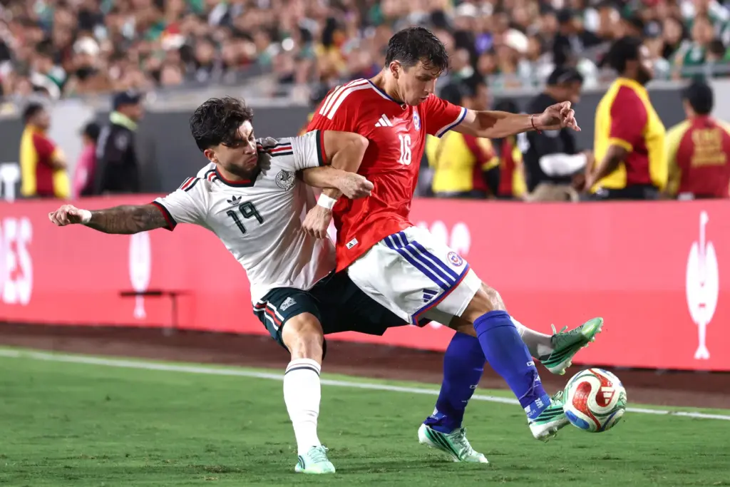 Mexico midfielder Denzell, left, vies for the ball with Chile...