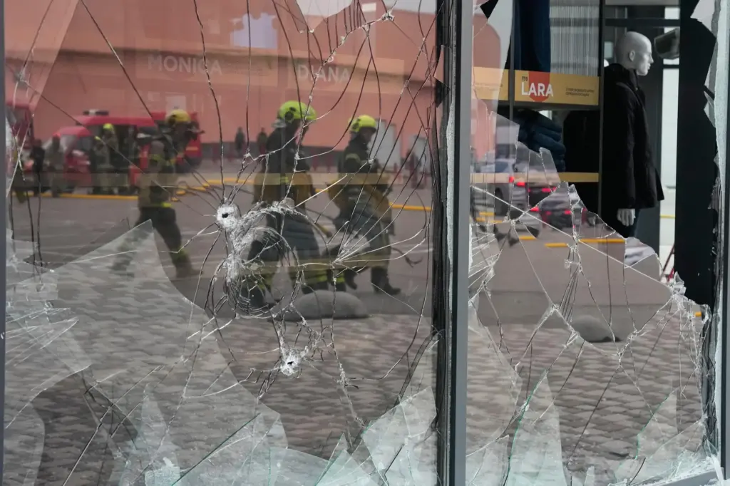 Firefighters are reflected in the broken glass after a Russian...