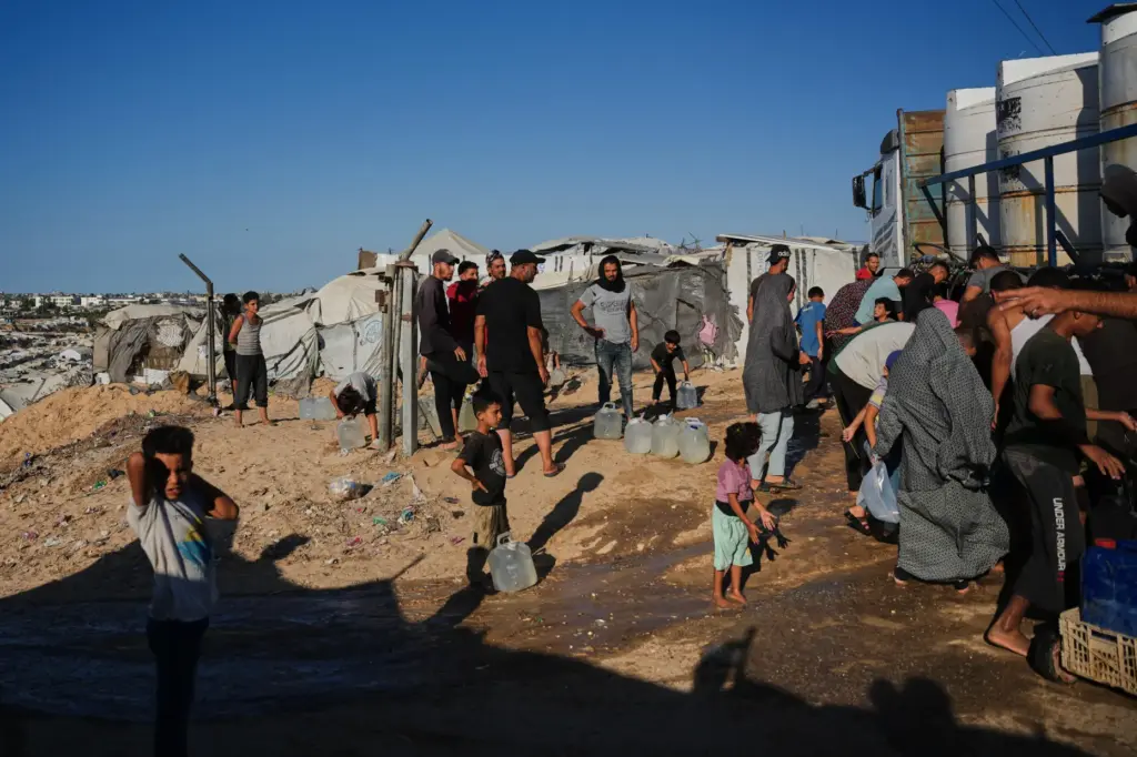 Displaced Palestinians gather to collect fresh water from a water...