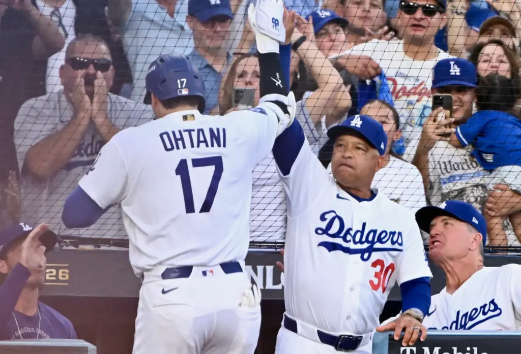Dodgers star Shohei Ohtani, left, high-fives Manager Dave Roberts as...