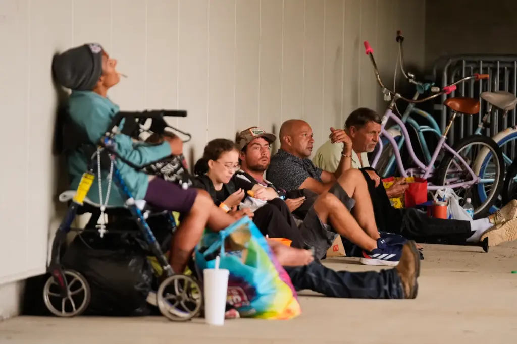 People sit outside an evacuation shelter as Hurricane Isaias approaches...