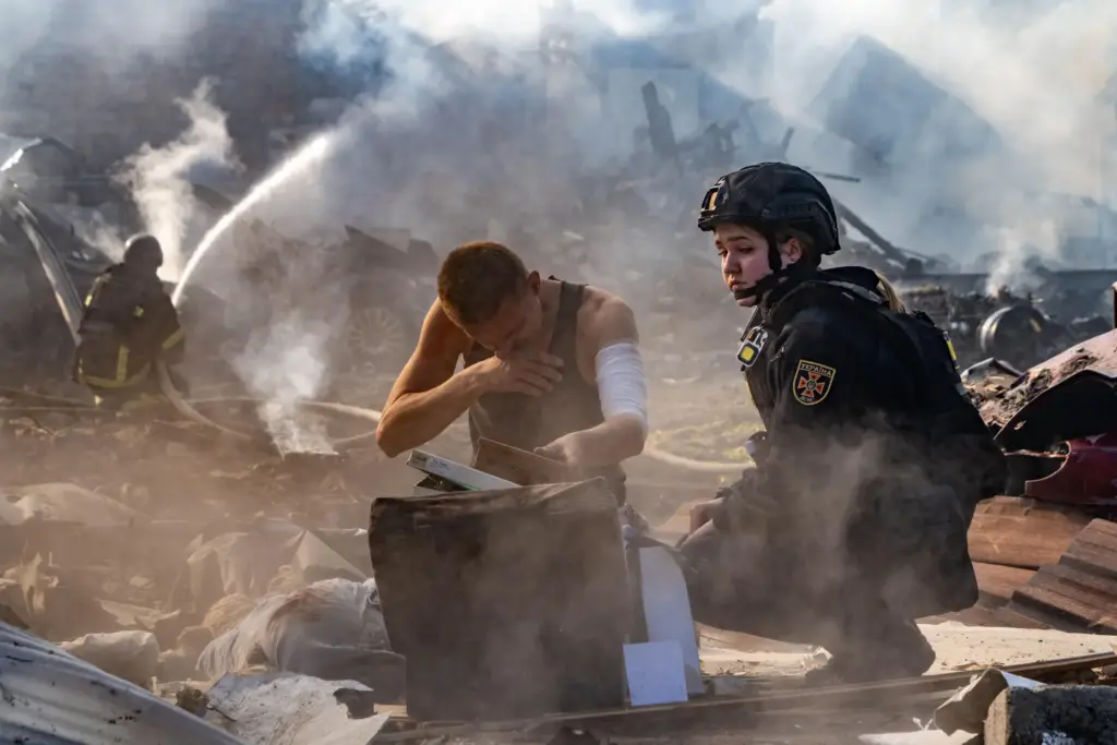 An injured man collects his belongings in front of his house destroyed in a Russian strike.