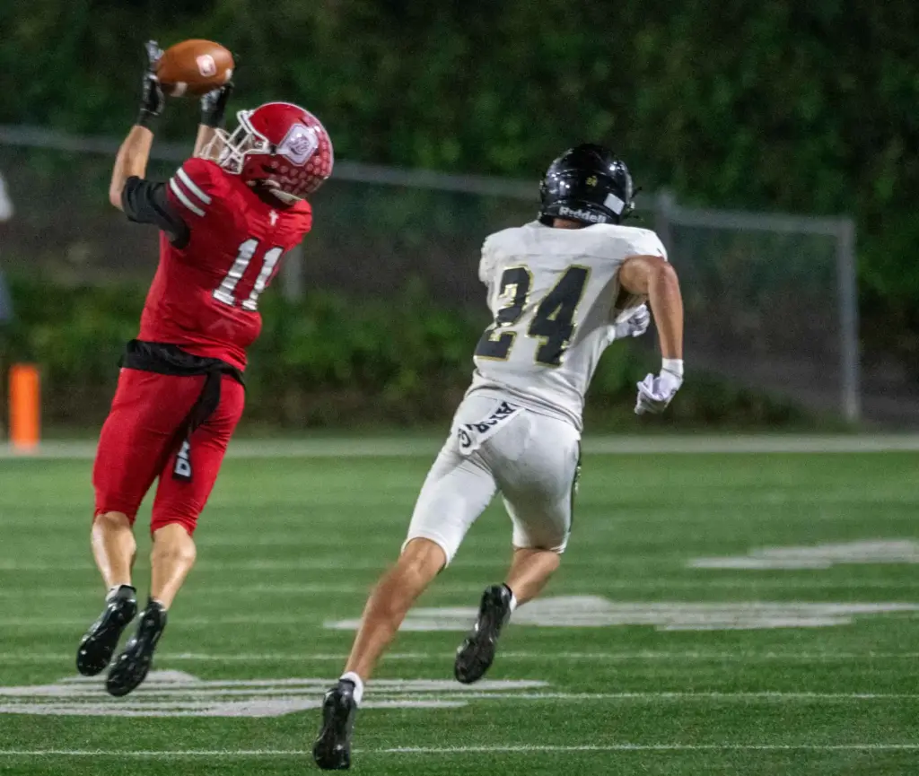 Orange Lutheran’s Raiden Velasquez (11) hauls in a pass and...