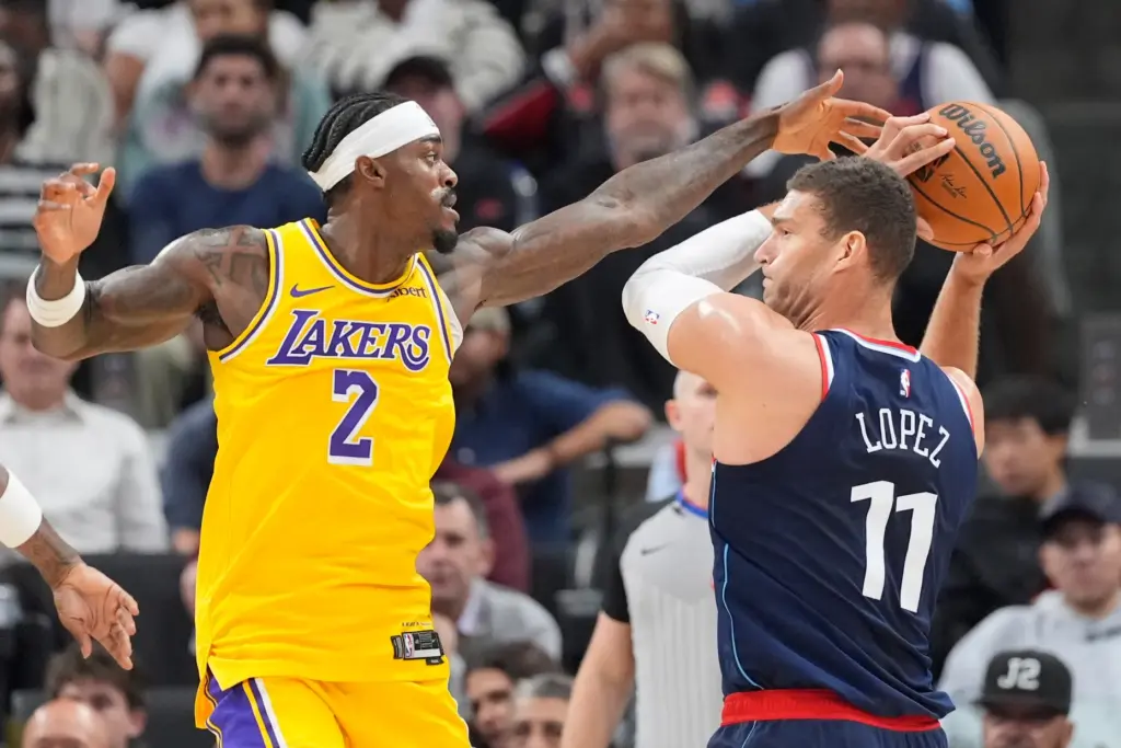 Clippers center Brook Lopez, right, tries to pass the ball...
