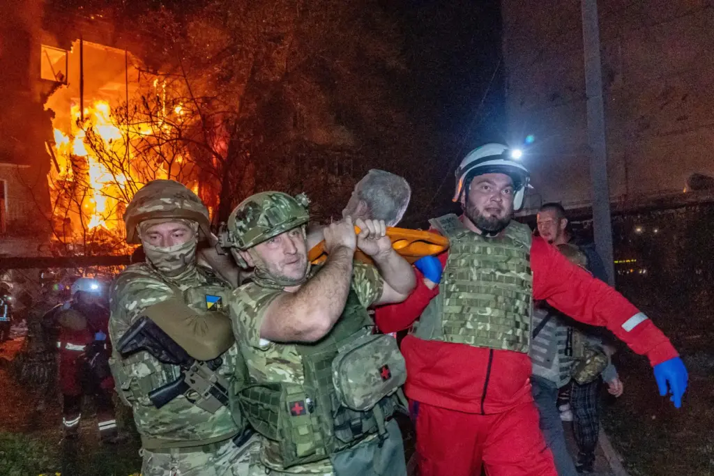 Rescuers evacuate an injured civilian after a residential building was hit in a Russian air attack.