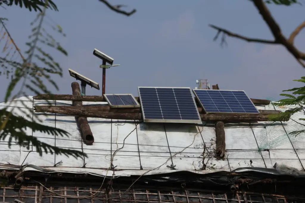 Solar panels sit on top of makeshift shelters to power...