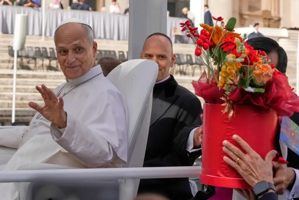 Pope Leo XIV is presented with flowers.