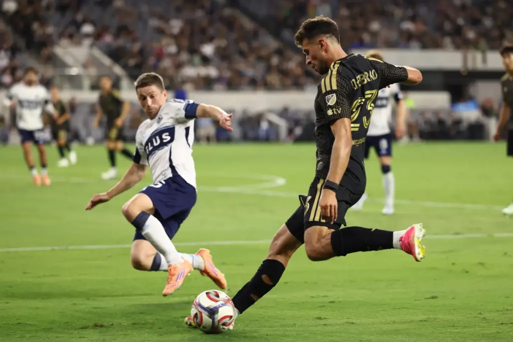 Los Angeles FC defender Yevhen Cheberko, right, winds up to...