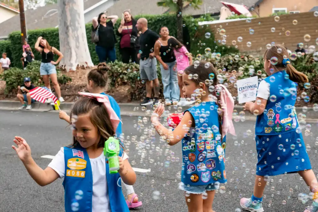 Daisy Girl Scouts from Troop 4086 blow bubbles while walking...