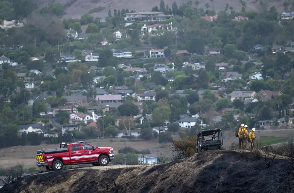 Los Angeles firefighters continue to assess the burned landscape around...