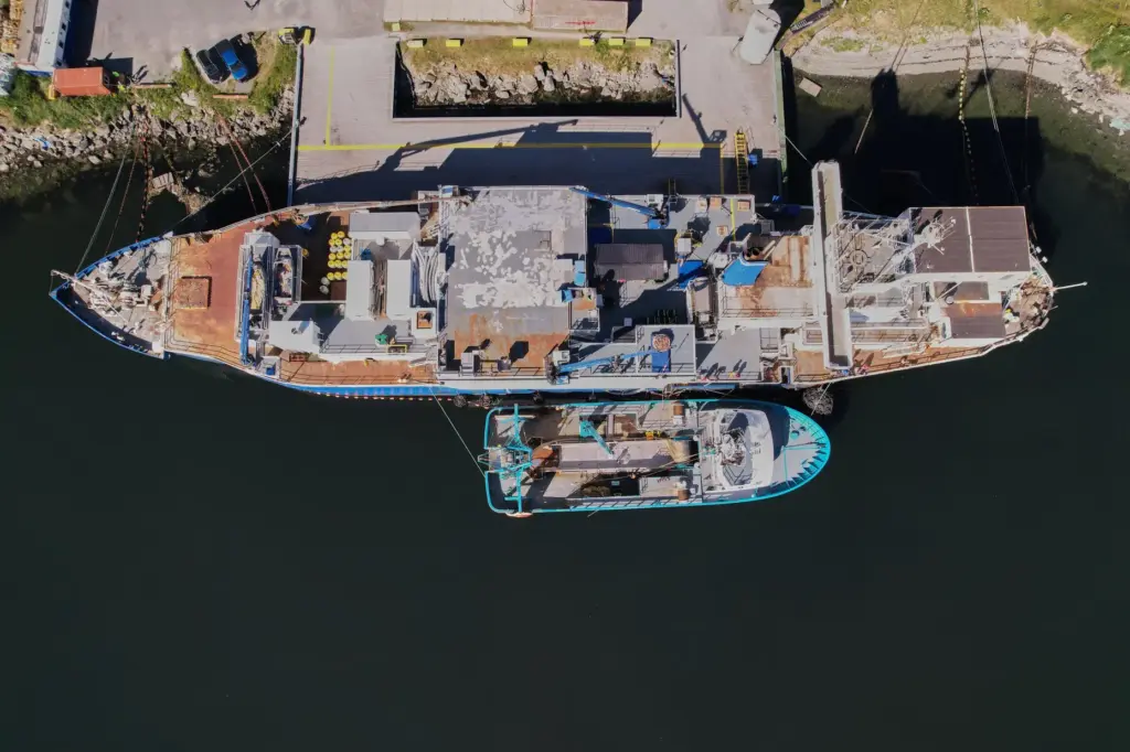 The F/V Progress, bottom, delivers its catch to a processing...