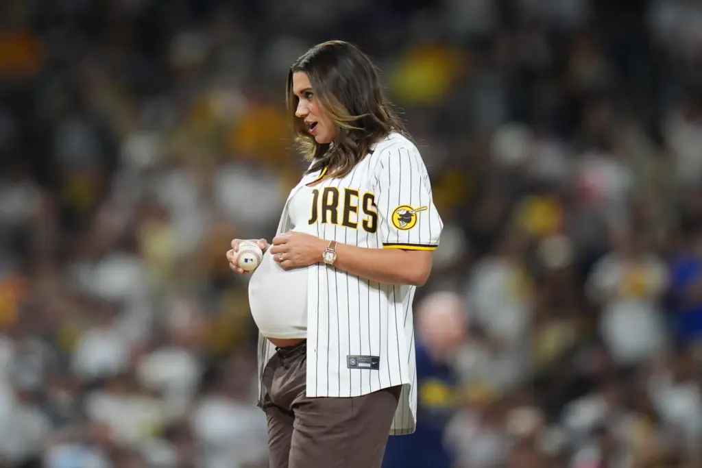 Former soccer player Alex Morgan rubs a baseball on her...