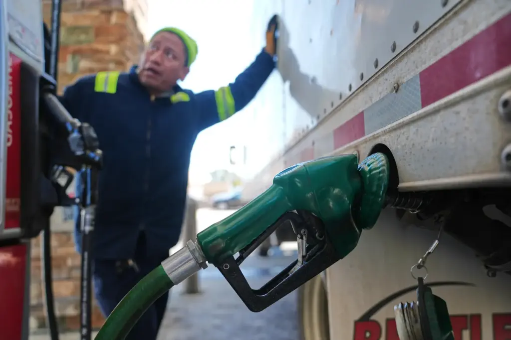 A driver watches the pump as he refuels his vehicle...