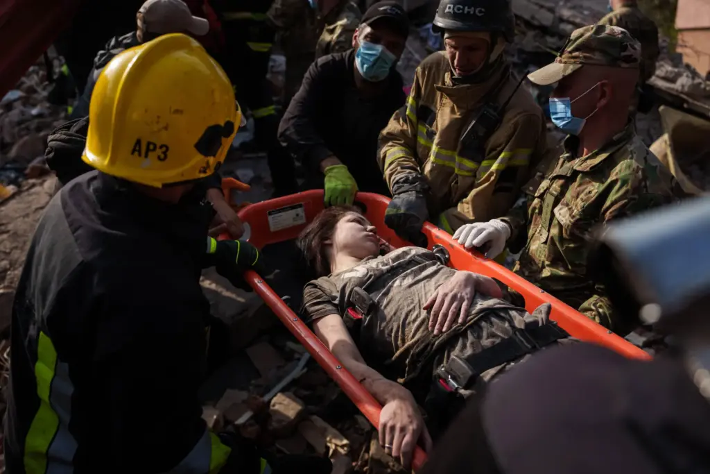 Locals and rescuers carry an injured woman from a building destroyed in a Russian strike.