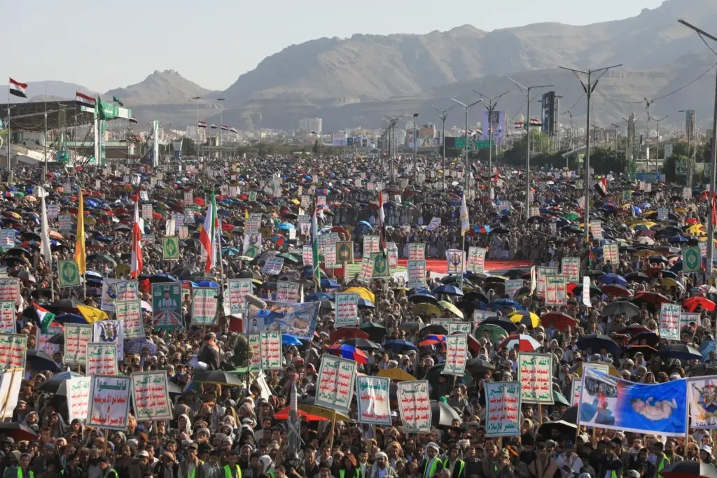 Supporters of Yemen’s Houthi rebels raise Yemeni and Iranian flags...
