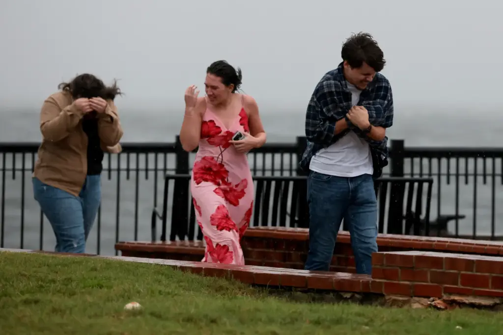 People walk through the wind and rain as Hurricane Isaias...
