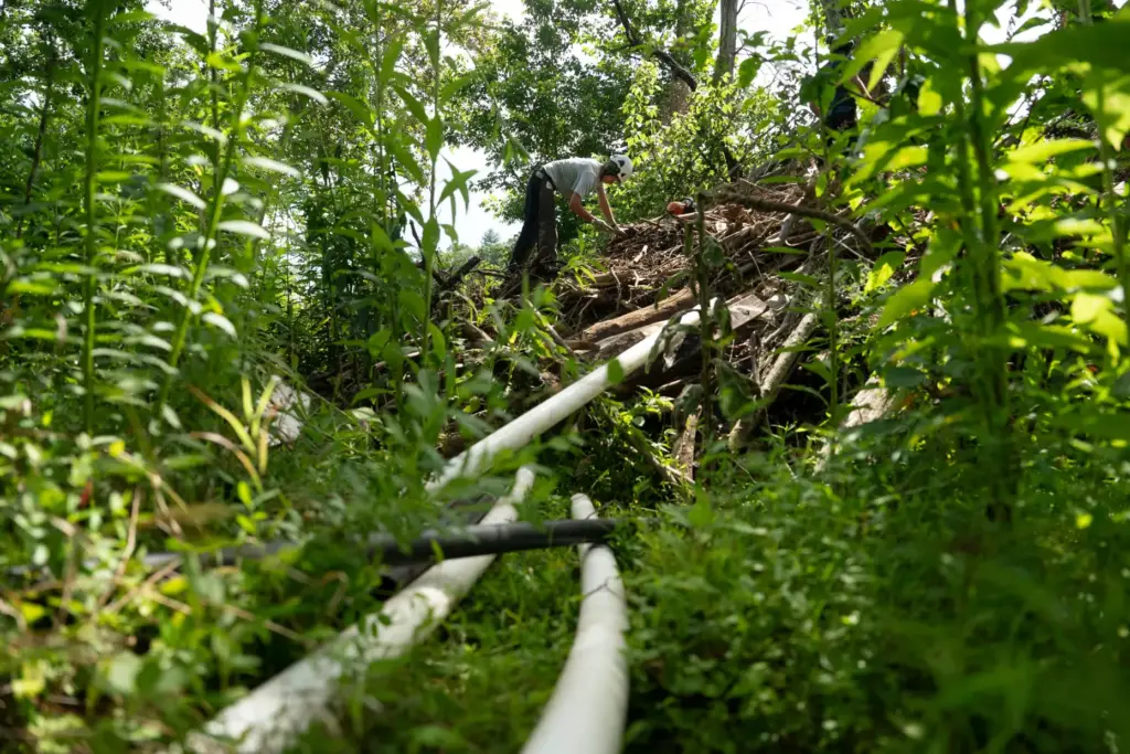 Workers from MountainTrue clear IPEX PVC pipe from the riverbank...