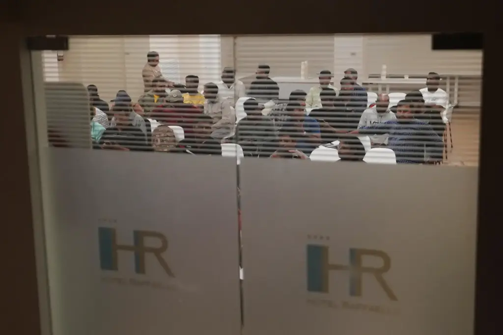 Caddell workers gather in a hotel conference room to wait...