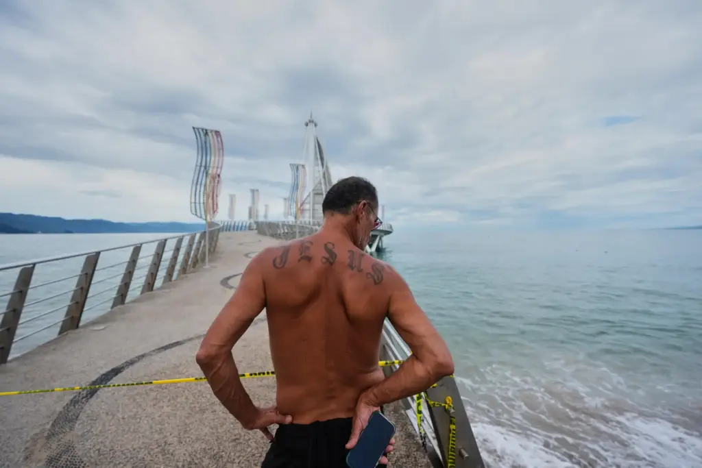A man stands at the entrance to a pier closed...