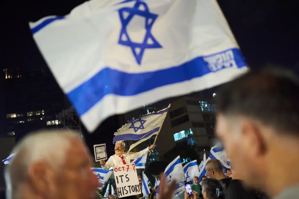 A demonstrator wearing a mask depicting Israeli Prime Minister Benjamin...
