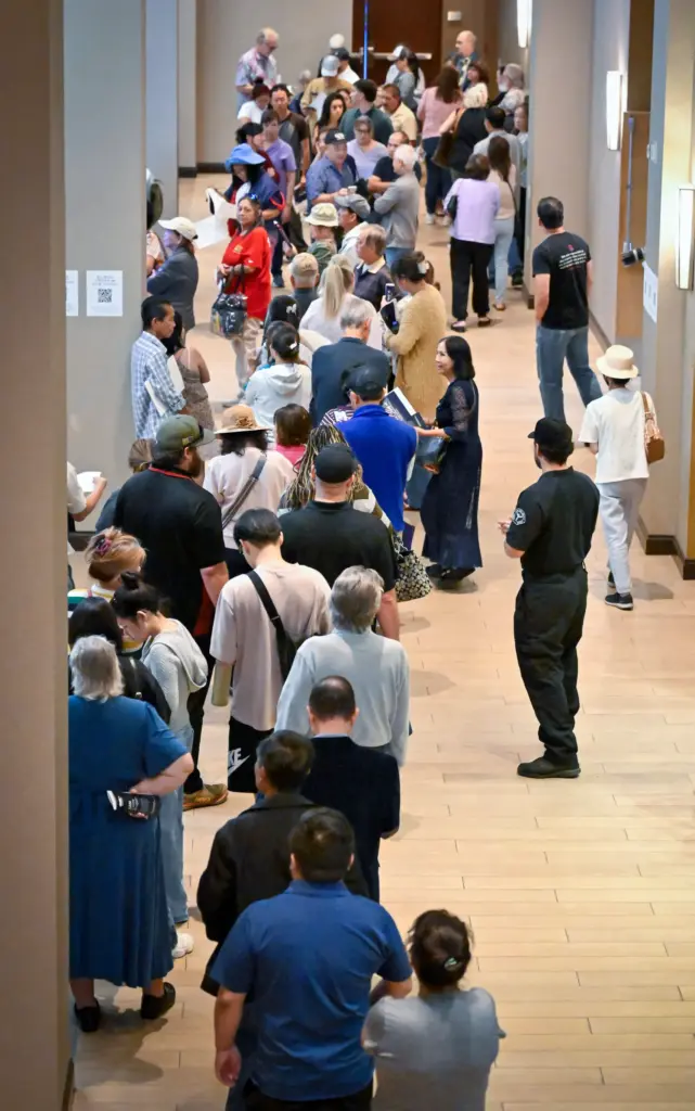 People wait in line to enter a meeting held at...