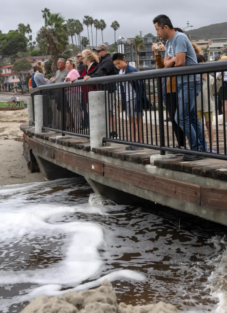 People stand on the Main Beach boardwalk in Laguna and...