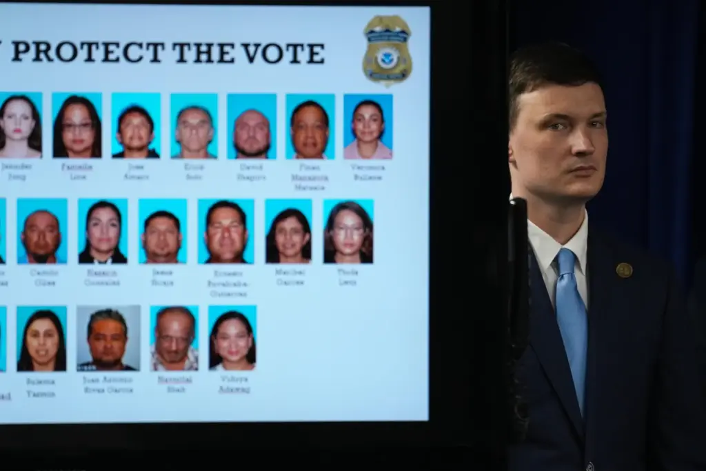 Acting U.S. Deputy Attorney General Trent McCotter stands next to a display of people charged.